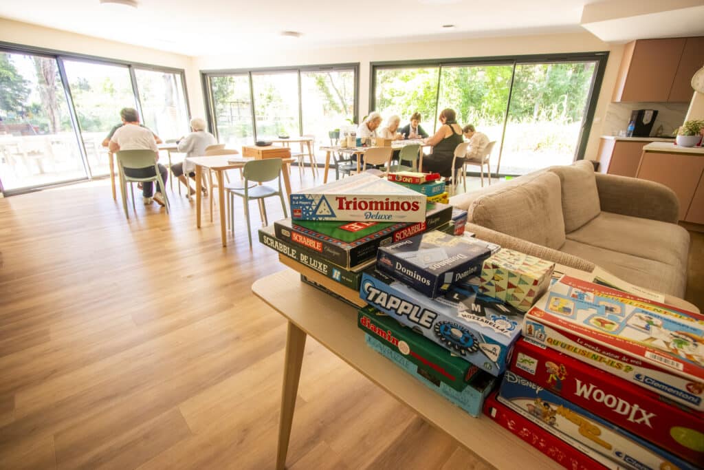 Activités et jeux de société Scrabble pour seniors Seniors jouant avec pile de jeux Triominos et Scrabble.