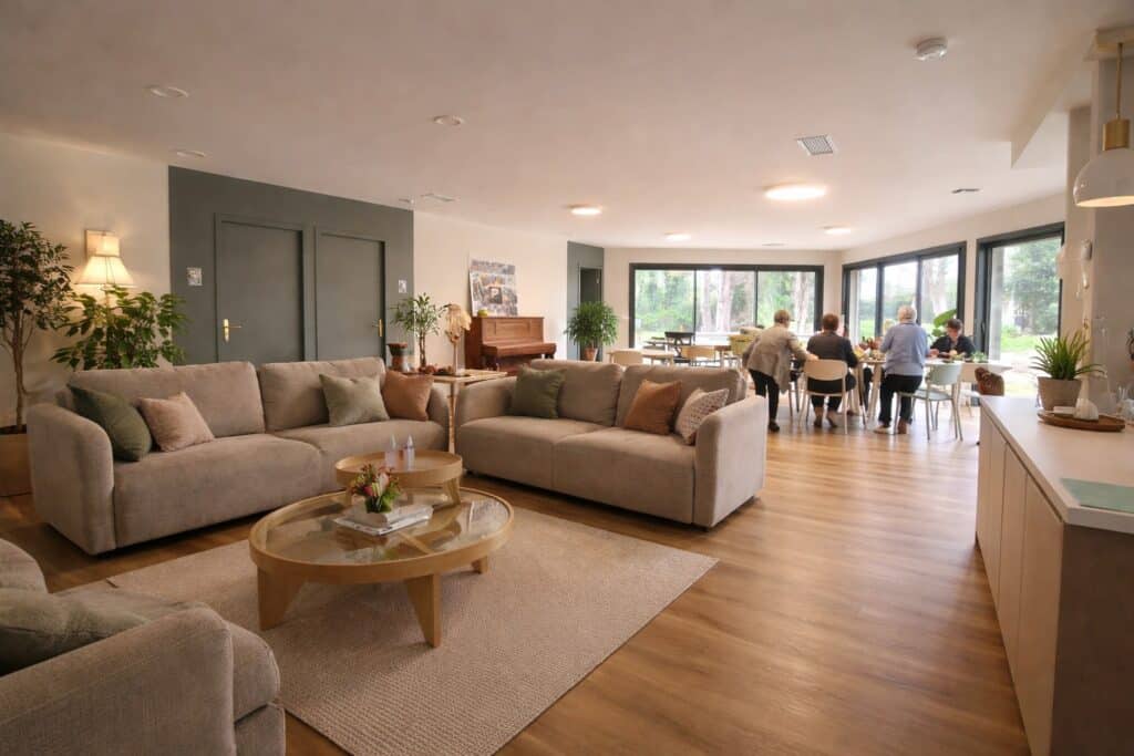 Salon et Salle à Manger Partagés Lumineux et Conviviaux Salon spacieux avec canapés confortables et coin repas convivial pour seniors baigné de lumière naturelle.